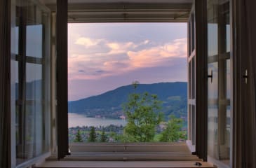 Stunning sunset view over water through an open window from a home featured in Jason Anson’s real estate listings, offering expert buyer's agent services.